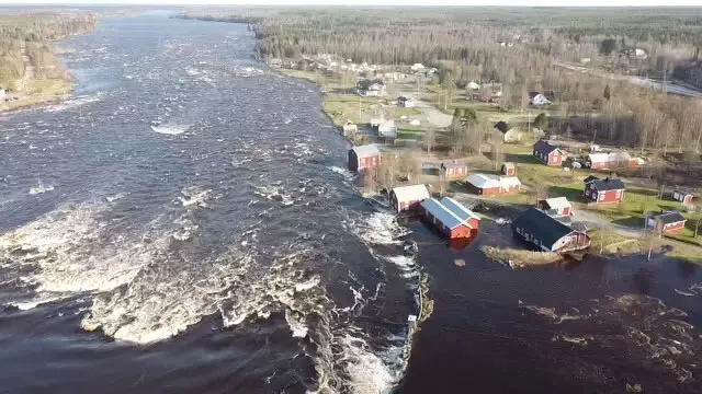 Forsande vatten med översvämmade byggnader intill älven