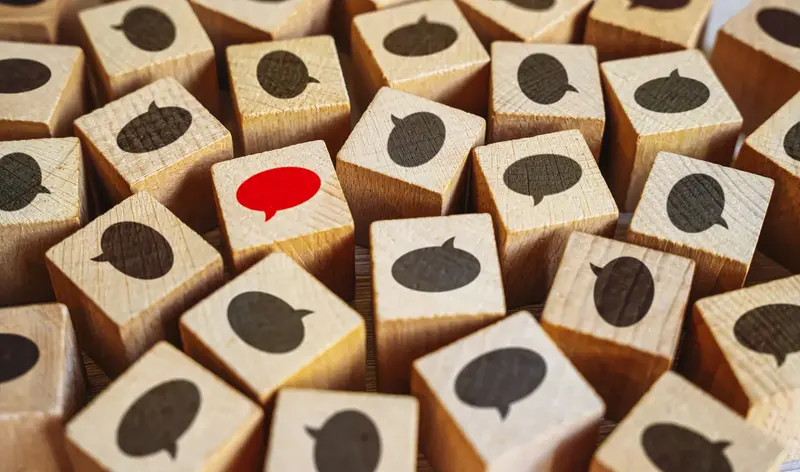 Bilden visar träklossar, på dem symboler av pratbubbor.