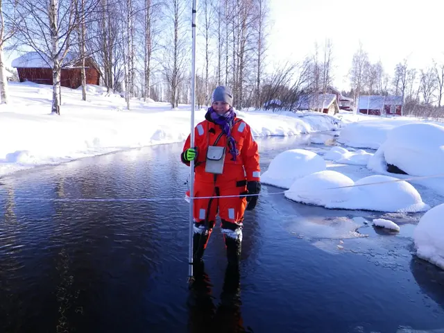 Person i orangea kläder i vatten med snö runt